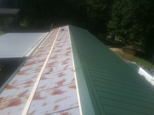 Old rusted panels beside newly installed green metal roofing — Wind Damage Roof Repair by Roofing Brothers in Southlake