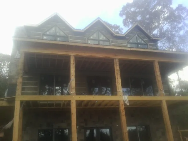 Dormers and porch framing on a large log home under construction — Roof Coating work by our crew in Southlake
