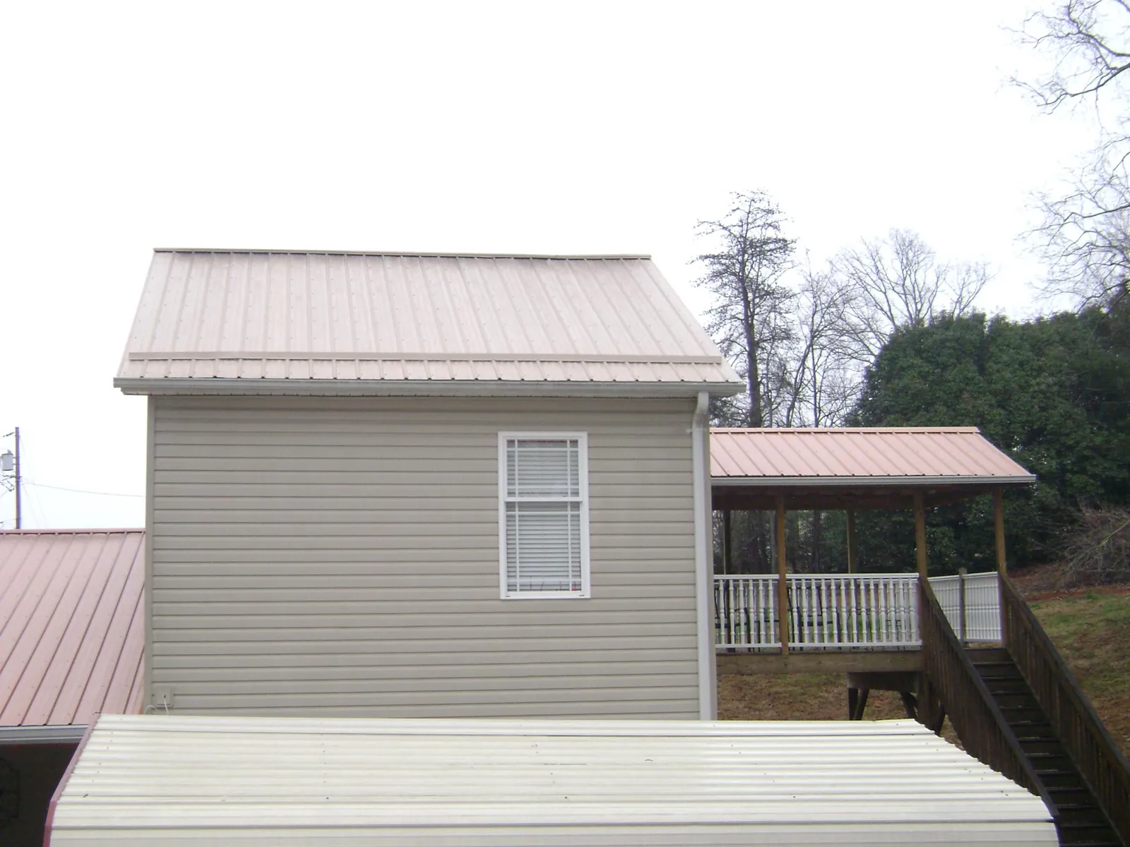 Tan metal roofs on a two story addition and attached porch, from a Roof Replacement job in Southlake