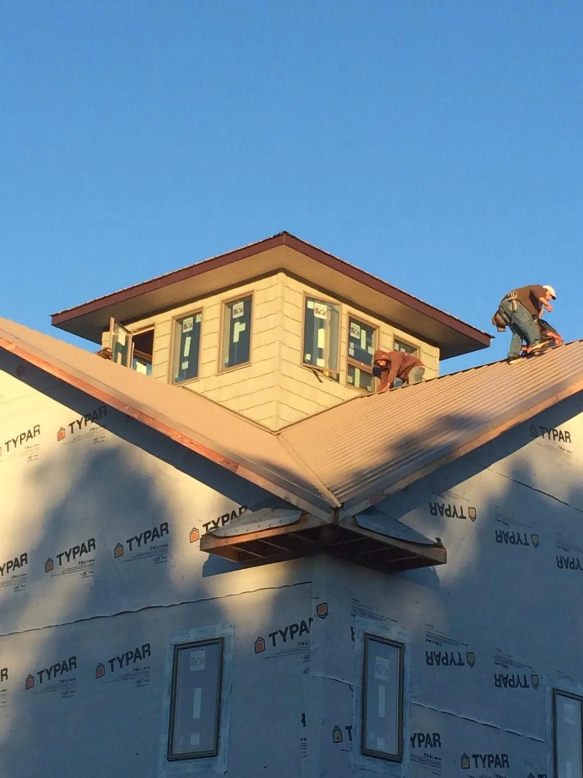Roofers working around a rooftop cupola on a new metal roof at sunset — Roof Waterproofing in Southlake by Roofing Brothers